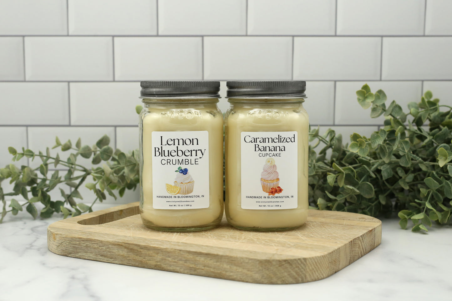 Spring and Summer Candle Club candles featuring Lemon Blueberry Crumble and Caramelized Banana Cupcake in 16 oz mason jars on a wooden board
