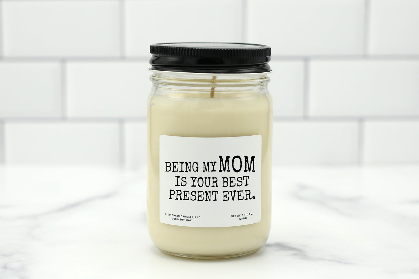 A 10 oz handmade soy wax candle with the label "Being My Mom Is Your Best Present Ever"—a funny Mother’s Day gift available in 10 custom scents.