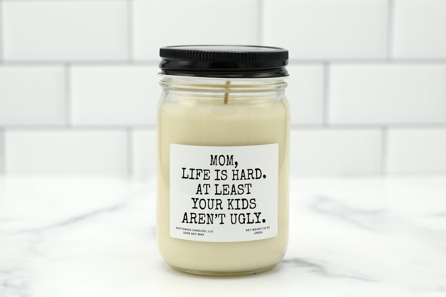 A 10 oz handmade soy wax candle with the label "Mom, Life Is Hard. At Least Your Kids Aren’t Ugly"—a funny Mother’s Day gift available in 10 custom scents.