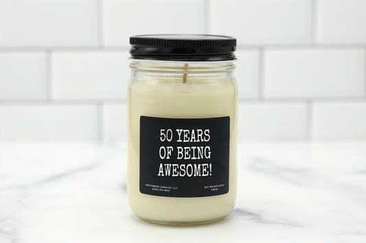 A 10 oz handmade soy wax candle with the label "50 Years of Being Awesome!"—a fun, celebratory birthday gift available in 10 scent options.