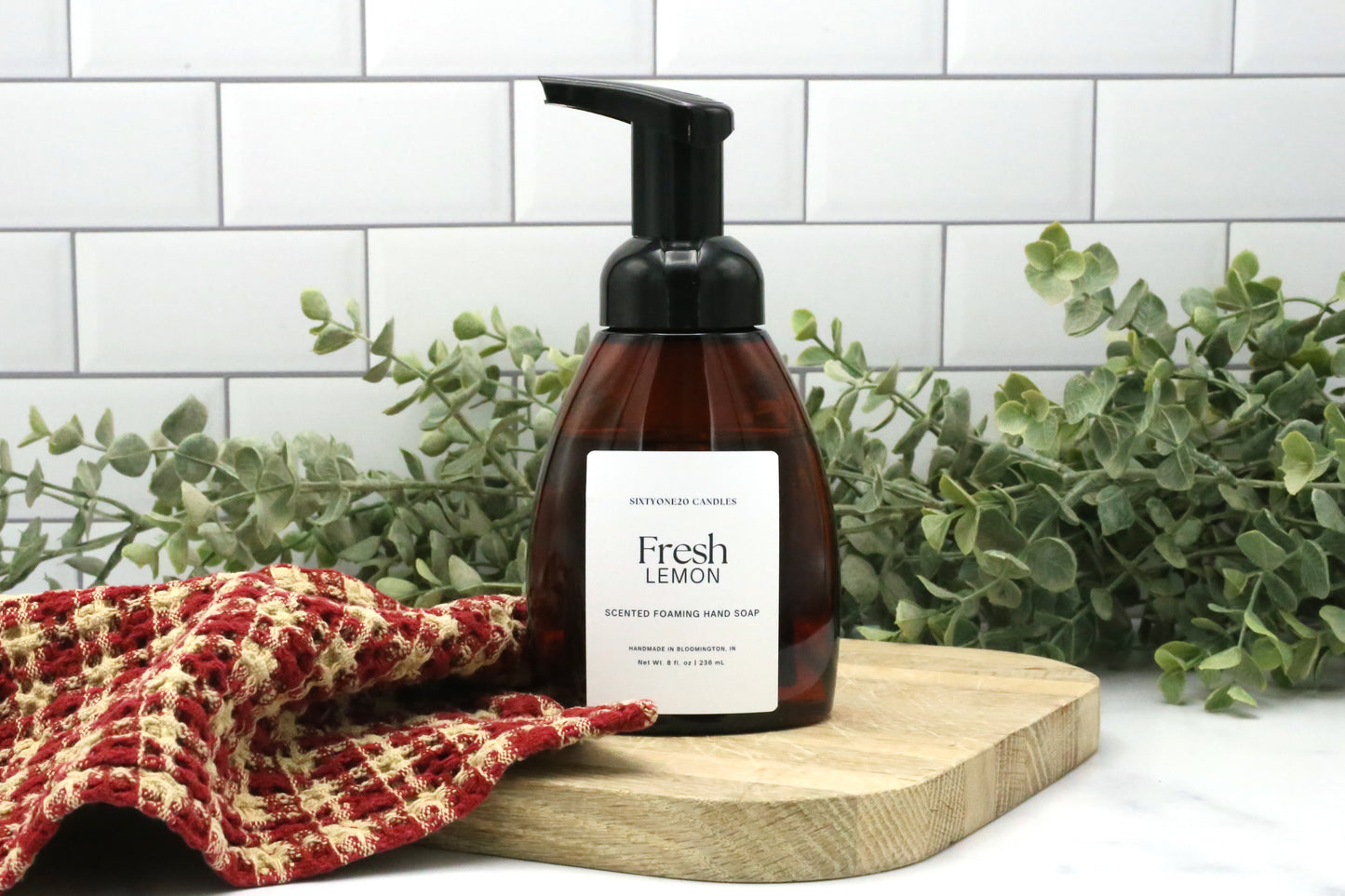 Fresh Lemon foaming hand soap by Sixtyone20 Candles on a wooden board with red towel and greenery background