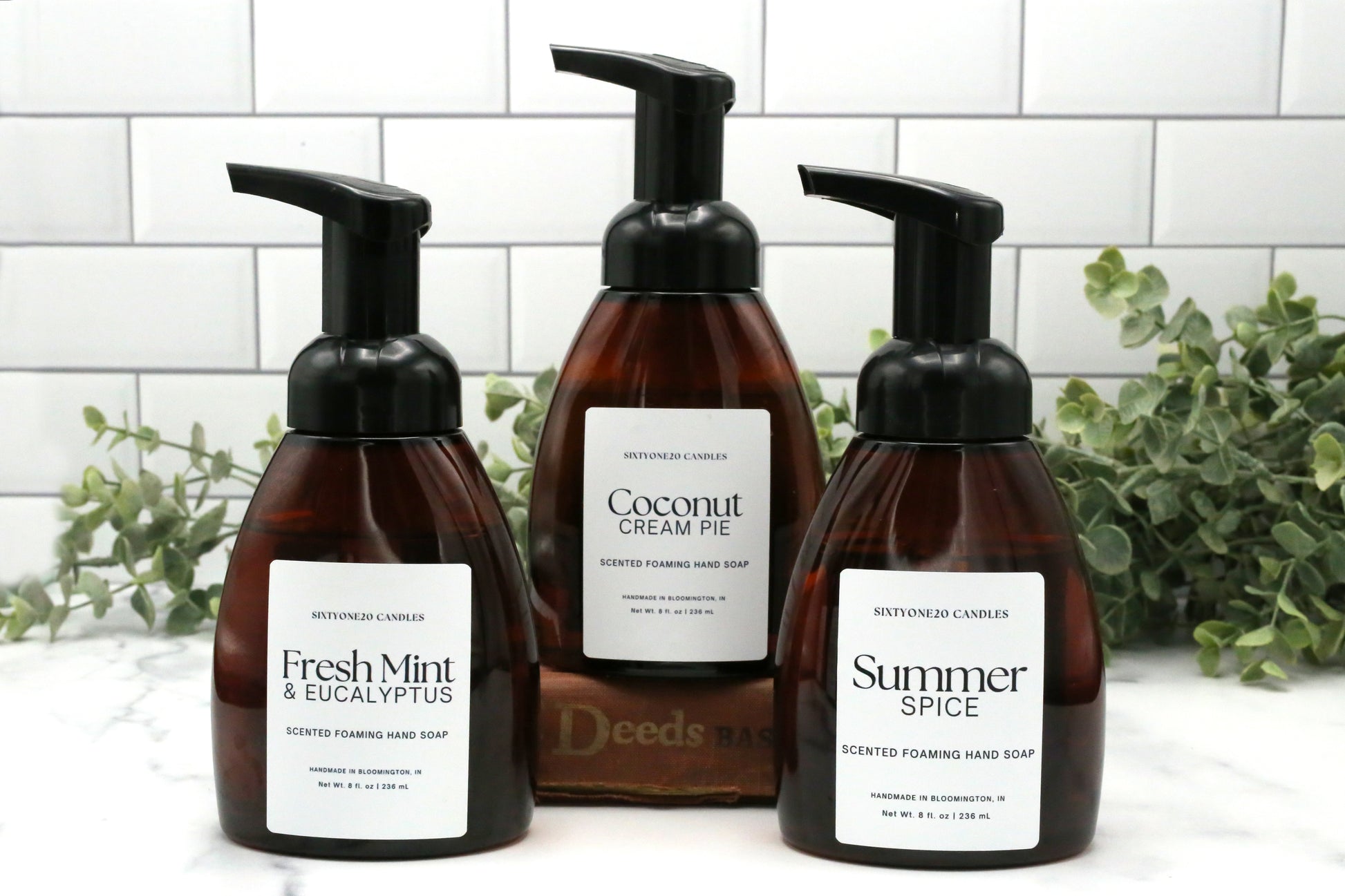 Three Sixtyone20 Candles foaming hand soaps in Coconut Cream Pie, Fresh Mint & Eucalyptus, and Summer Spice scents on white tile with greenery