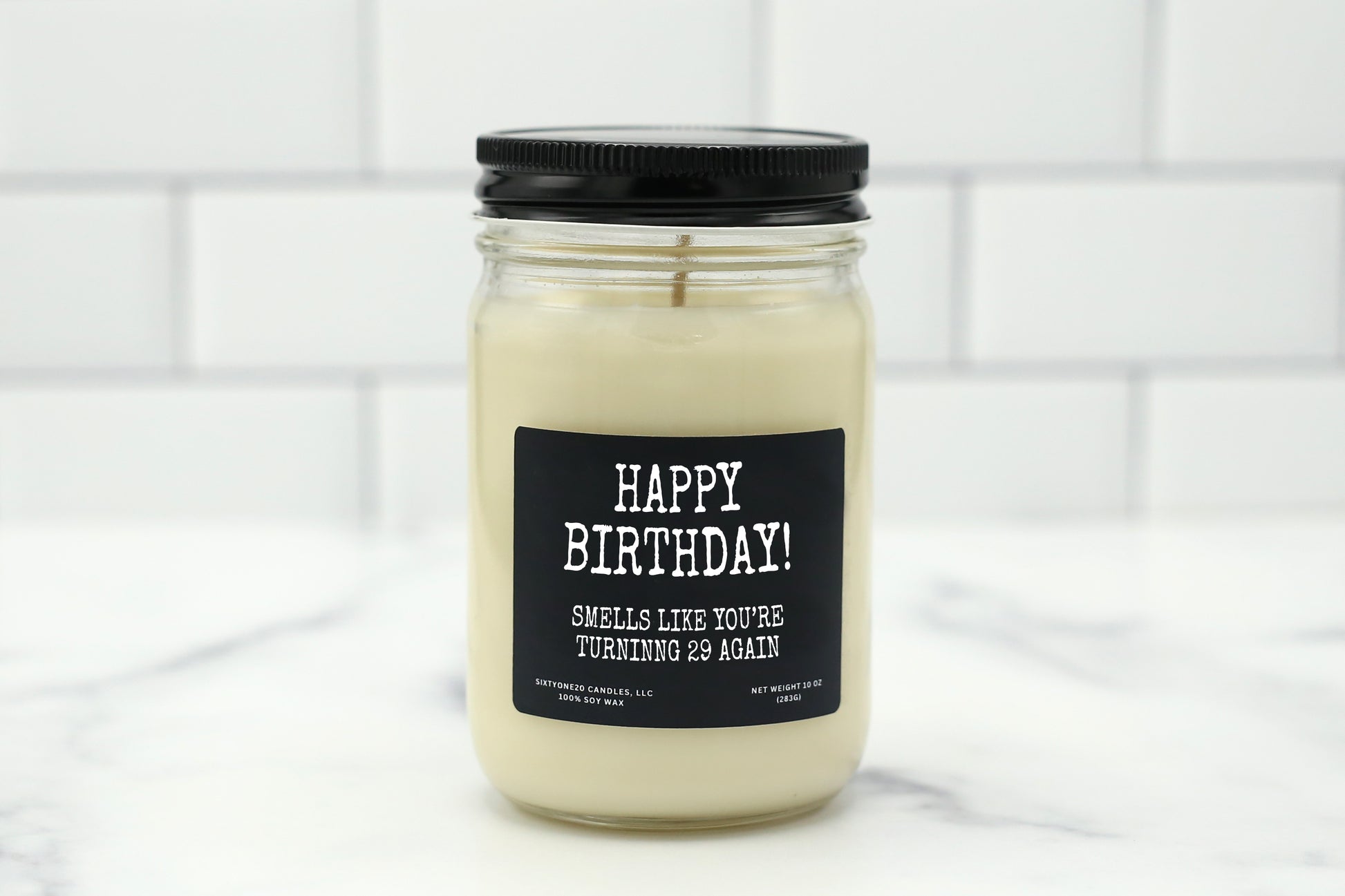 A 10 oz handmade soy wax candle with the label "Happy Birthday! Smells Like You’re Turning 29 Again," a fun, humorous gift available in 10 scent options.