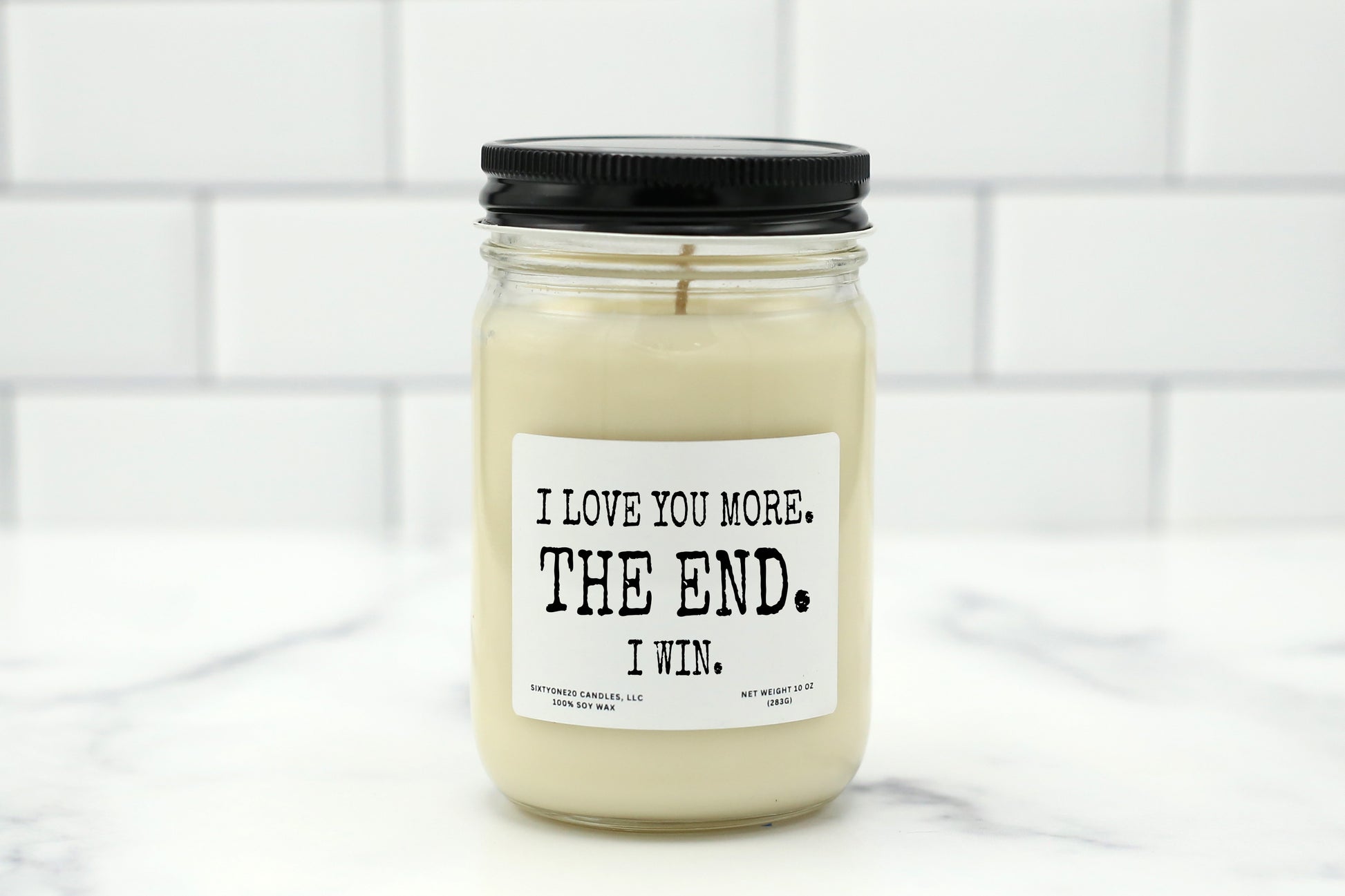 Soy wax candle with the label "I Love You More. The End. I Win." – a playful, funny gift for couples.