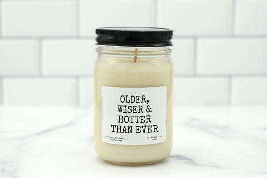 A 10 oz handmade soy wax candle with the label "Older, Wiser & Hotter Than Ever"—a fun, empowering birthday gift available in 10 custom scents.