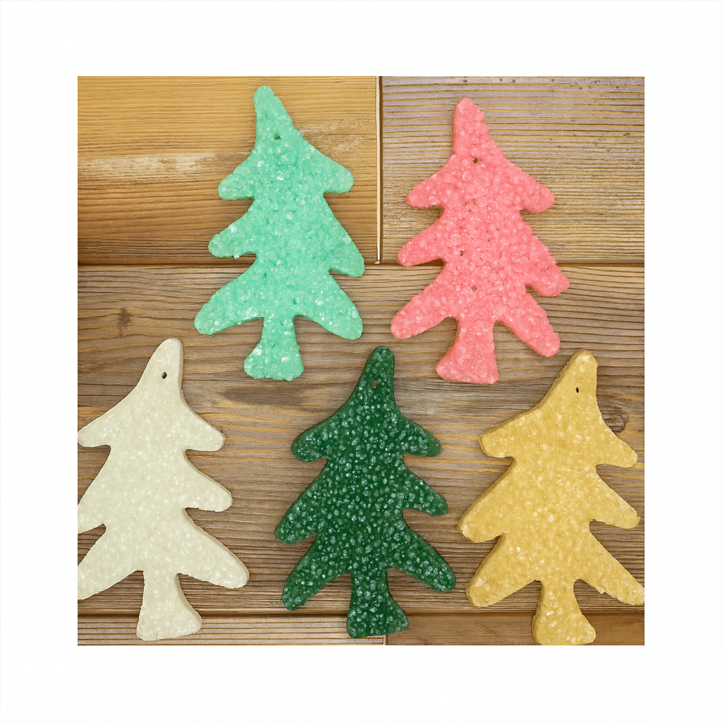 Five Christmas tree-shaped freshies are arranged in a semi-circle on a wooden surface. The colors include mint green, pink, dark green, creamy white, and golden yellow. Each freshie has a textured, crystal-like finish, and the image is framed with white borders for a square format.