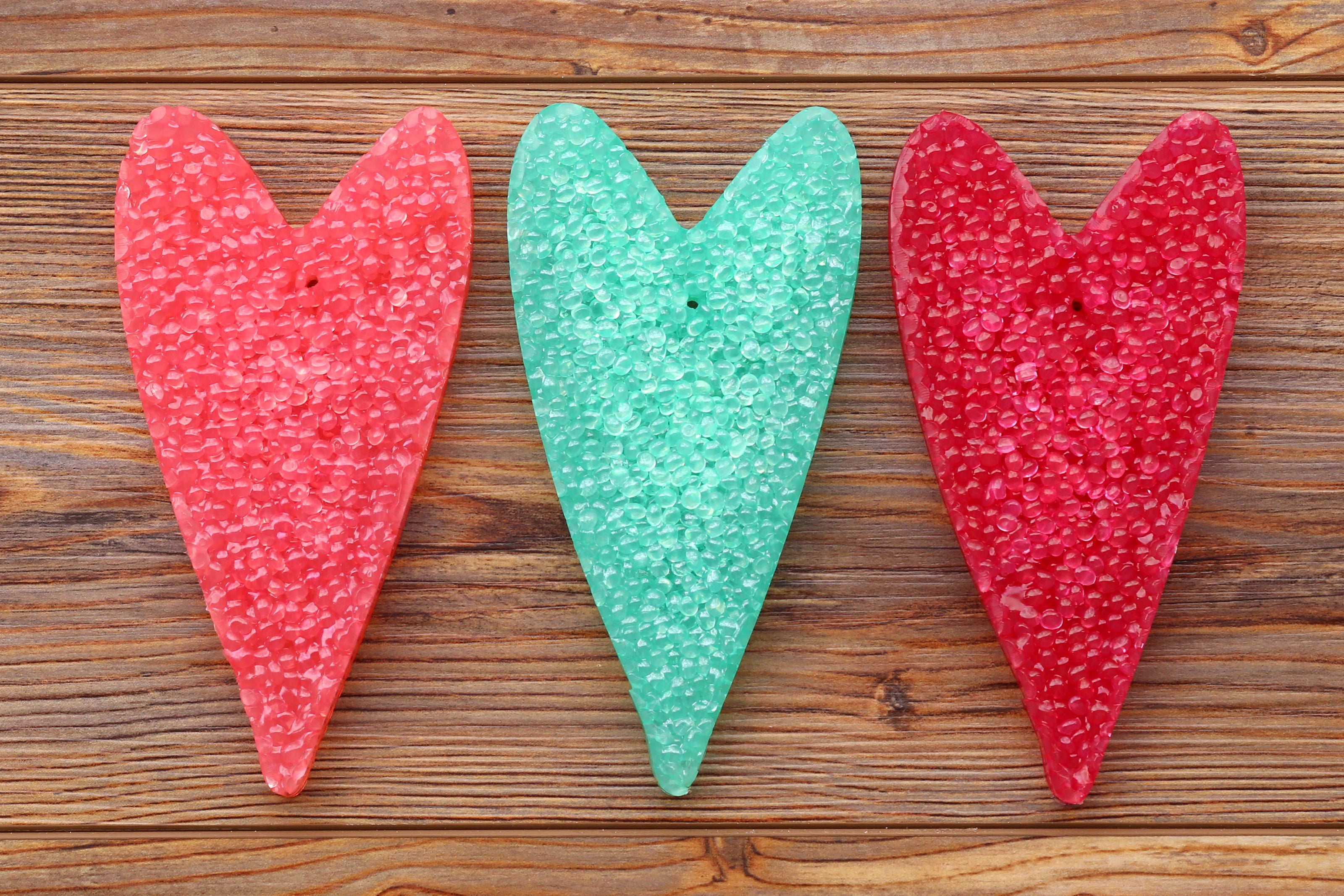 Three heart-shaped freshies with textured surfaces on a wooden background