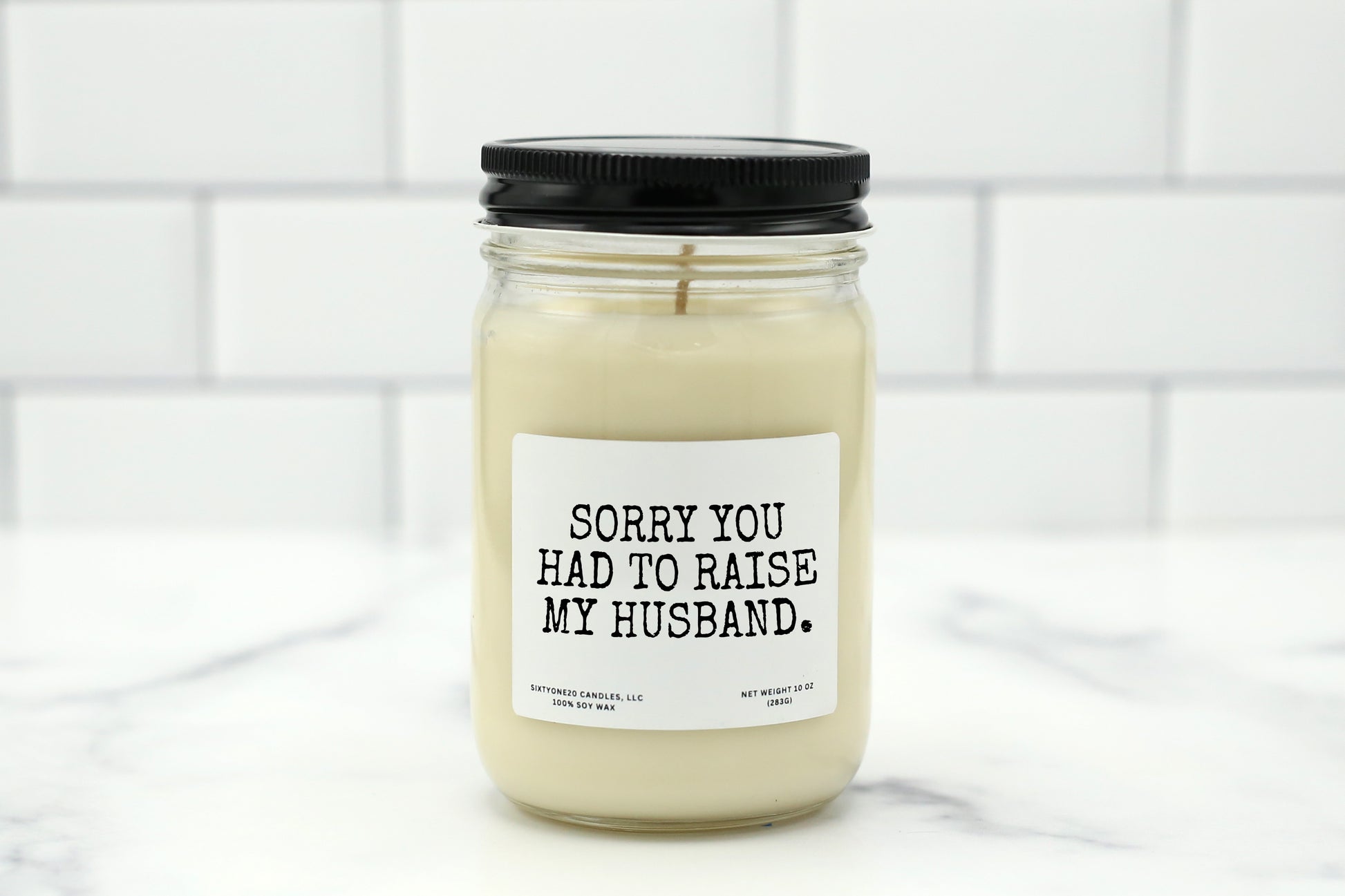A 10 oz handmade soy wax candle with the label "Sorry You Had to Raise My Husband"—a funny Mother’s Day gift for mothers-in-law, available in 10 custom scents.