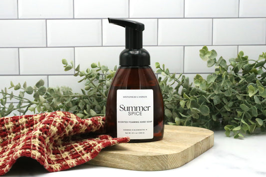 Summer Spice foaming hand soap by Sixtyone20 Candles on a wooden board with red towel and eucalyptus background