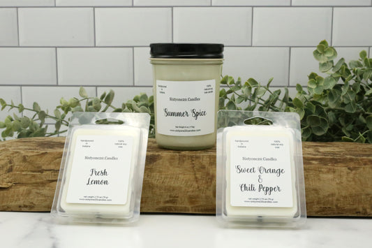 Summer Spice candle with Fresh Lemon and Sweet Orange & Chili Pepper wax melts from Sixtyone20 Candles, displayed on a wood slab with greenery in the background.
