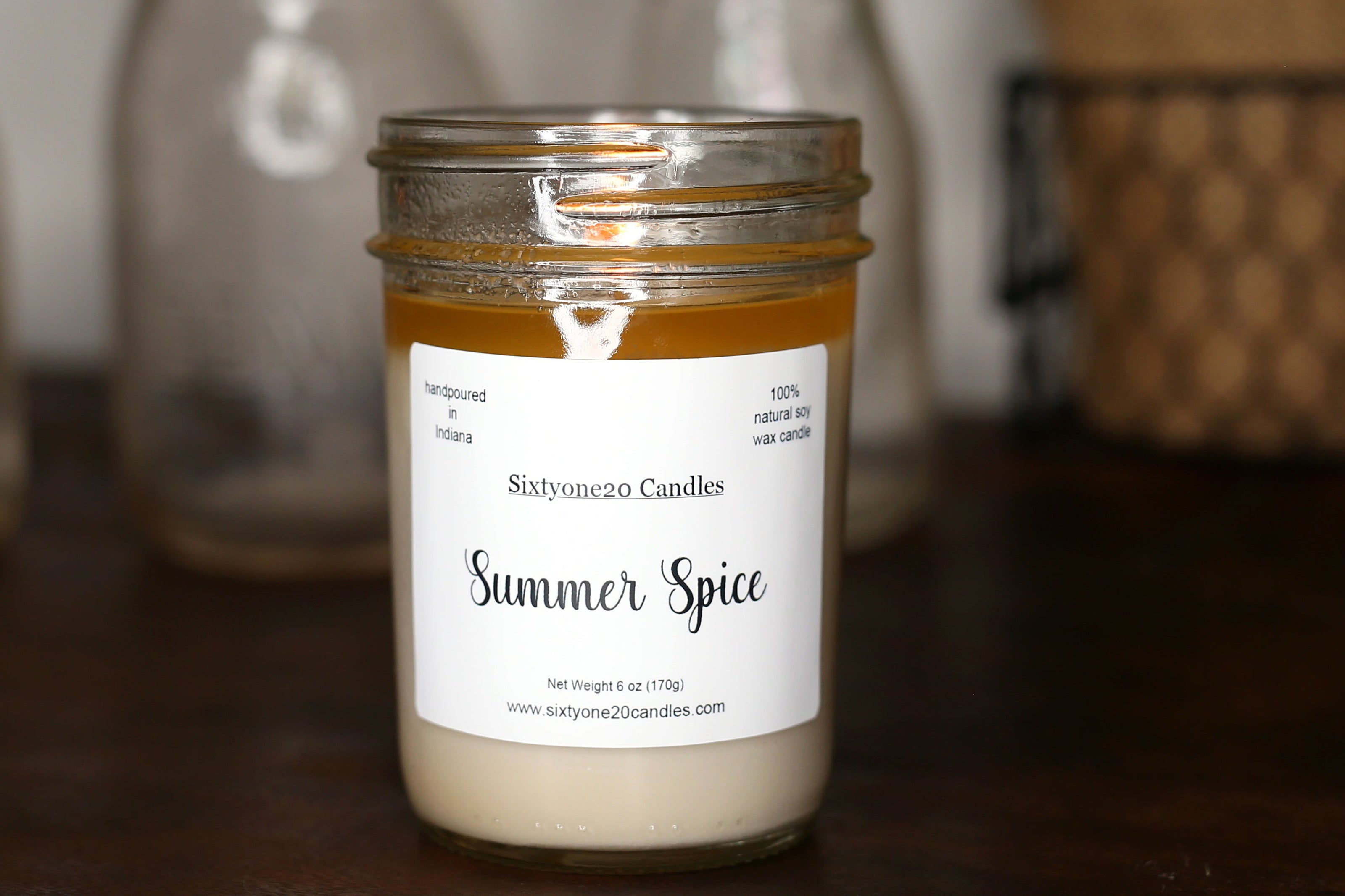 Jar of 'Summer Spice' candle with a label on a wooden surface, blurred background