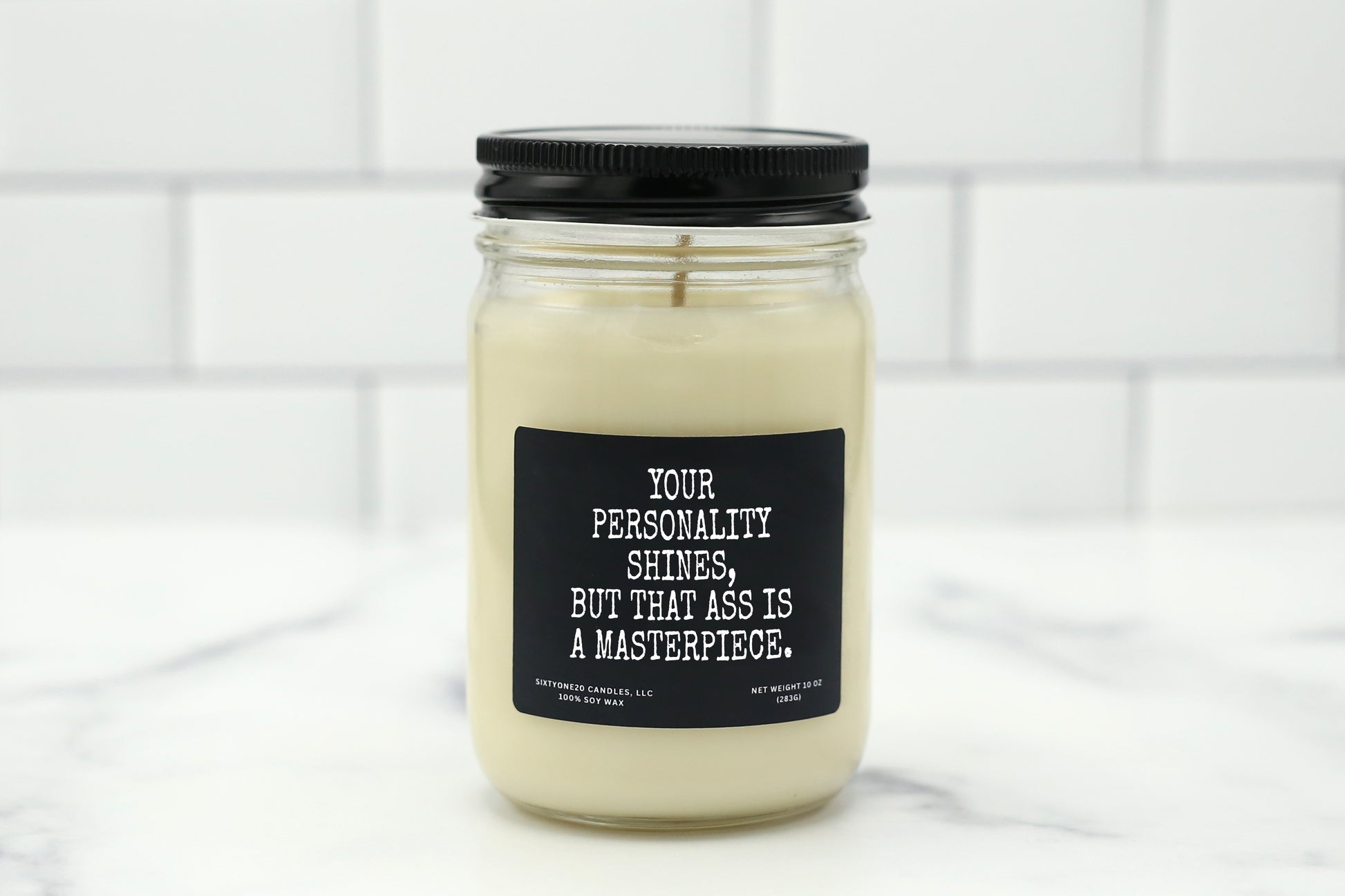 Soy wax candle with the label "Your Personality Shines, But That Ass Is a Masterpiece." – a bold, funny gift for flirty couples.