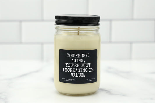 A 10 oz handmade soy wax candle with the label "You're Not Aging; You're Just Increasing in Value"—a funny birthday gift available in 10 custom scents.